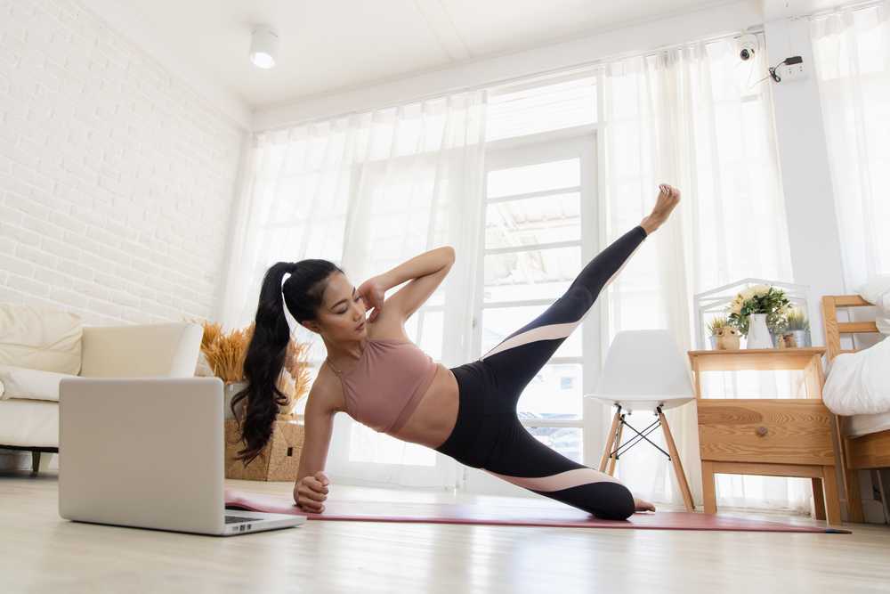 Manfaat Pilates sedang melakukan latihan Pilates di studio, fokus pada peregangan dan penguatan otot inti, menggambarkan bagaimana Pilates membantu meningkatkan fleksibilitas dan kekuatan tubuh