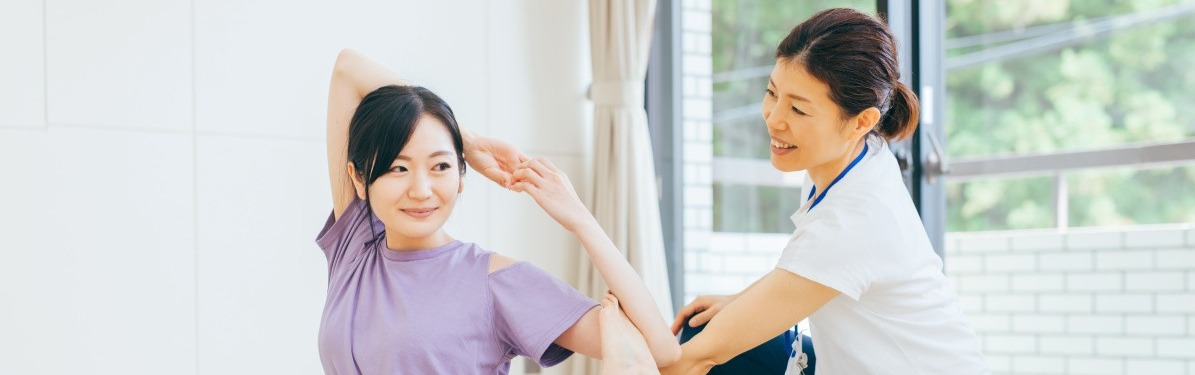 trainer helping woman stretch
